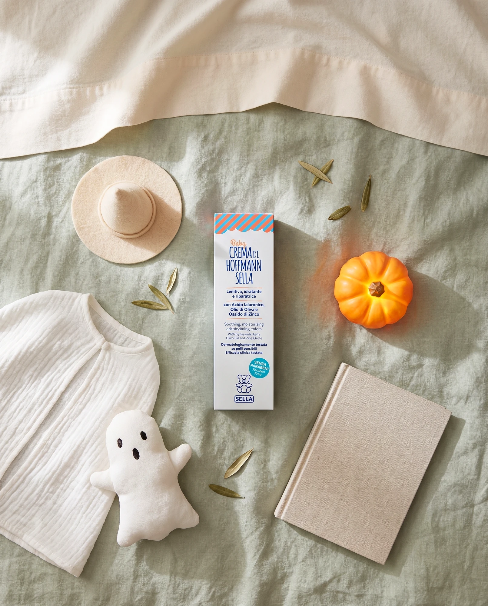Pack of Baby Crema di Hoffmann Sella on a blanket with a decorative pumpkin, a fabric ghost and a notebook