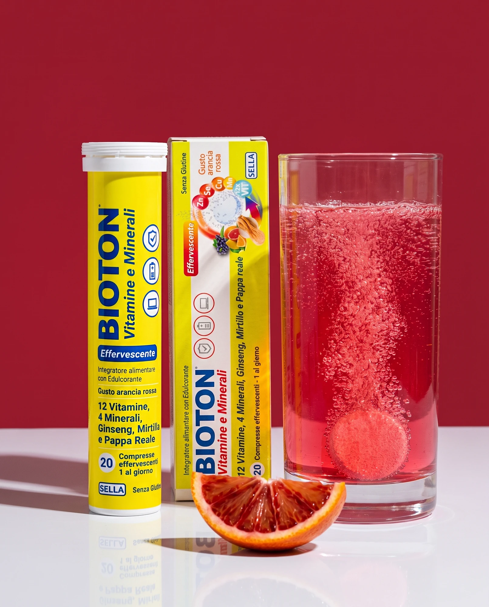 Tube and pack of effervescent Bioton Vitamine e Minerali with a glass of fizzy blood orange drink