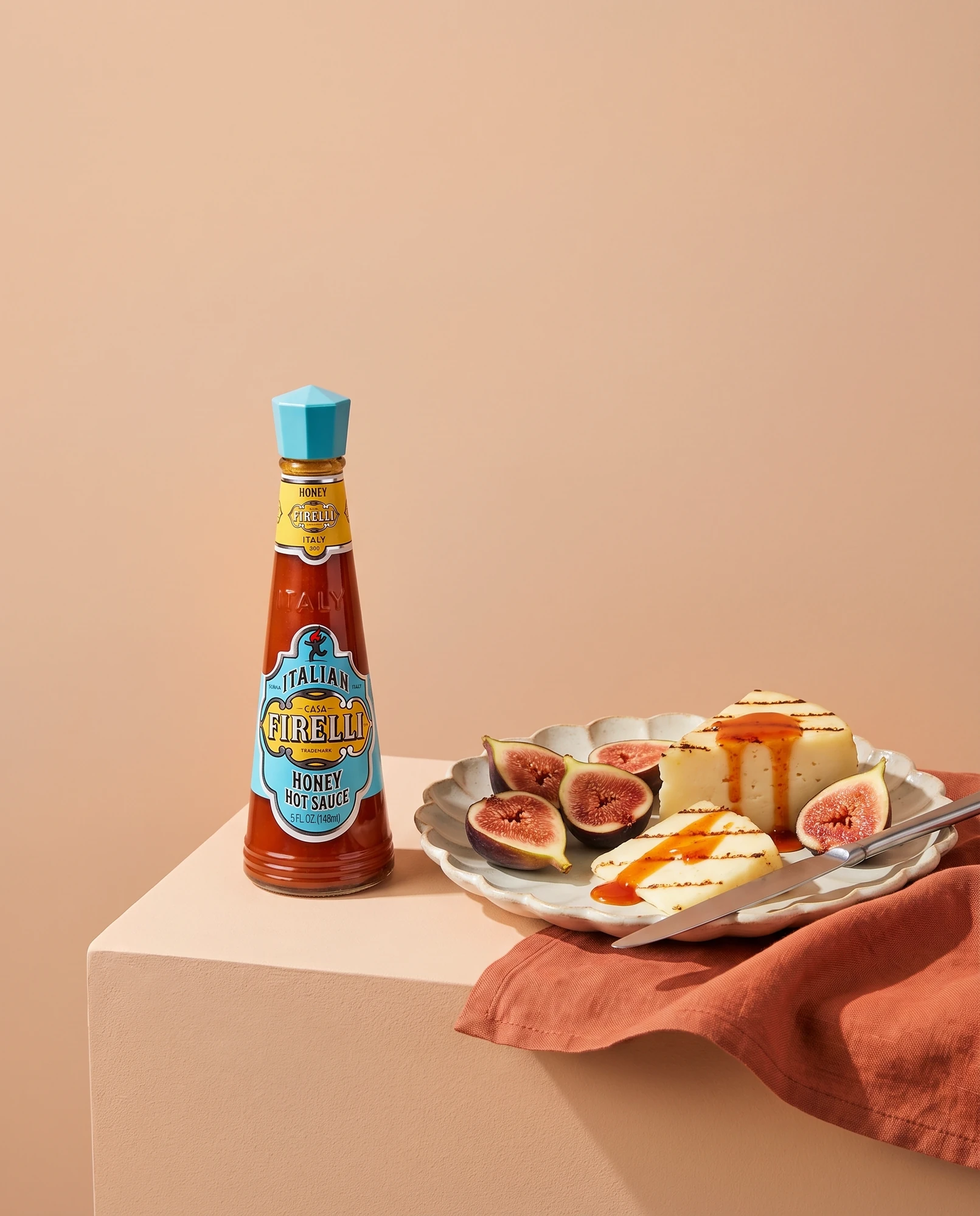 Bottle of Casa Firelli Honey Hot Sauce beside grilled cheese with figs and a drizzle of hot sauce