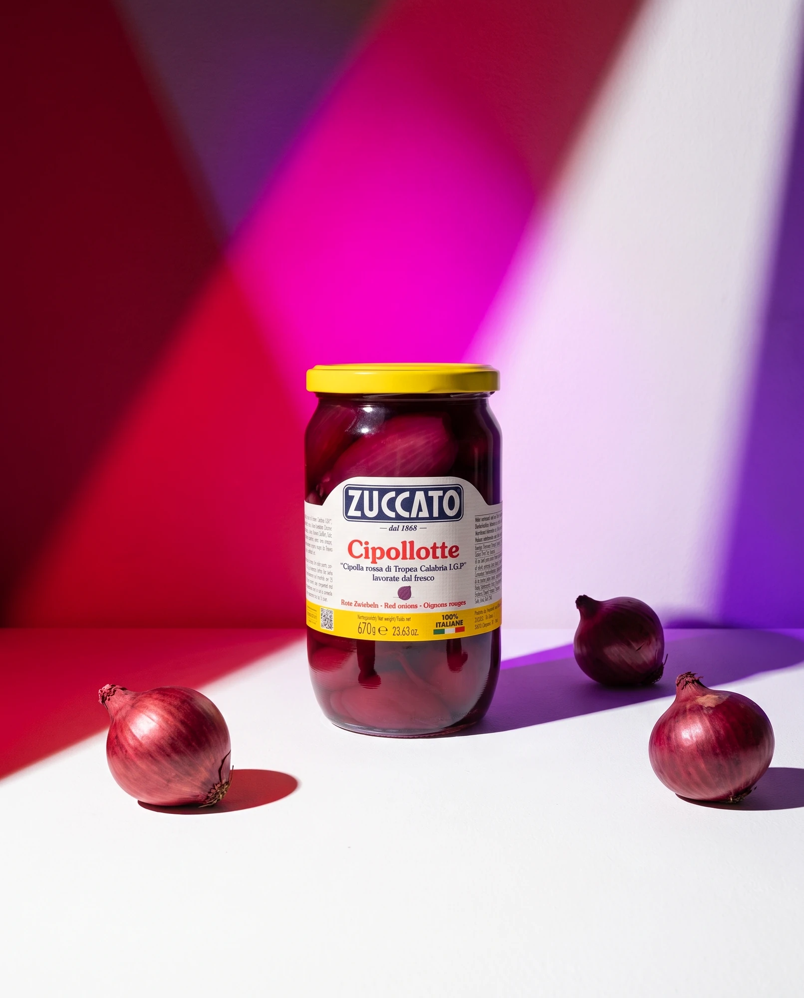 Jar of Zuccato Cipollotte di cipolla rossa di Tropea IGP with fresh onions and beams of coloured light